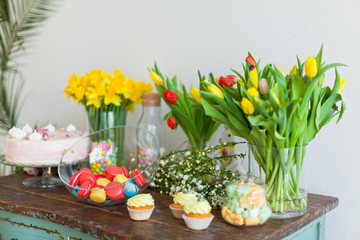 Bright macaroons and cupcakes on a wooden table