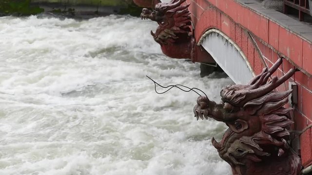 River flowing under a bridge with red dragon head sculptures in DuJiangYan, China