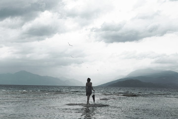 lonely woman looks at infinity and uncontaminated nature on a stormy day