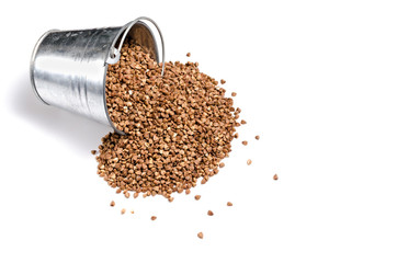 Buckwheat is scattered on a white background from a bucket