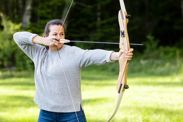 Female Archer Aiming With Bow And Arrow In Forest