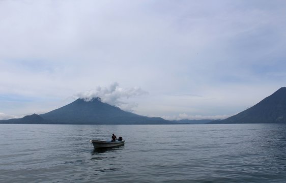 Barca solitaria sul lago Atitlan in Guatemala con un vulcano sullo sfondo