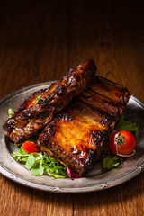 Roasted ribs, served on an old plate. Dark or balck background.
