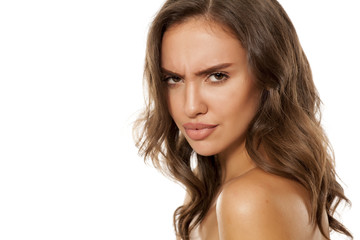 Portrait of beautiful young scowling woman on white background