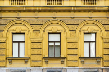 Old decorative building, yellow colored, with tree windows