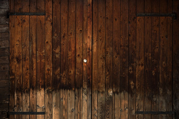 Old wooden door with black iron hinges, closed