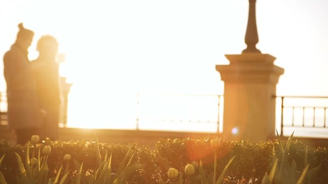 Two young ladies walking slowly along esplanade in slowmotion. Sun flare