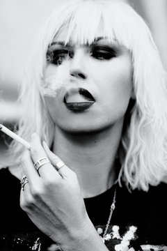 monochrome portrait of stylish blonde grunge young woman smoking cigarette