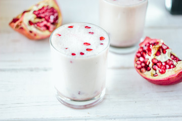 Traditional indian lassi - cold yougurt drink on white table with pomegranate seeds