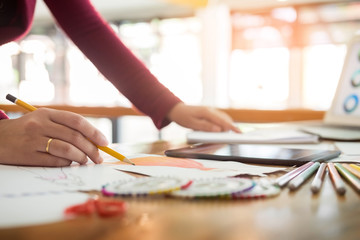 young women working as fashion designer drawing sketches for clothes in atelier paper at workplace studio.