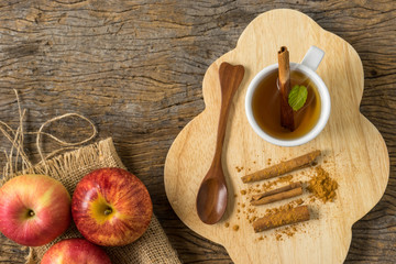 top view hot apple juice in cup with cinnamon and ground cinnamon on old wood. autumn food concept