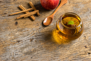 hot apple juice in glass with cinnamon on old wood. autumn food concept
