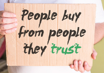 People Buy From People They Trust on cardboard in hands man 