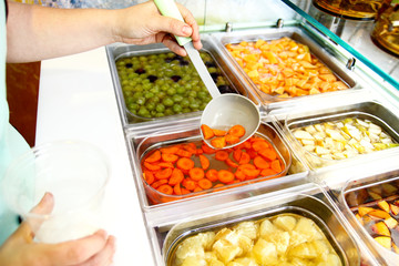 Set of fruit dessert for make a smoothie. Fresh fruits juices. The woman's hand making smoothie fruit, takes with ladle the fruit juice from the water and the fruit into a plastic cup. Healthy foods.