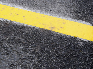 Gelbe Fahrbahnmarkierung auf Asphalt