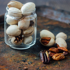 Pecan nuts inside glass jar on rustic surface.