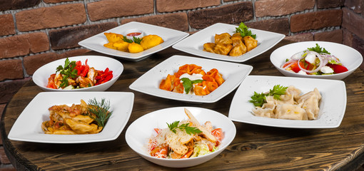 Set of different salads, dumplings and ravioli on a wooden table