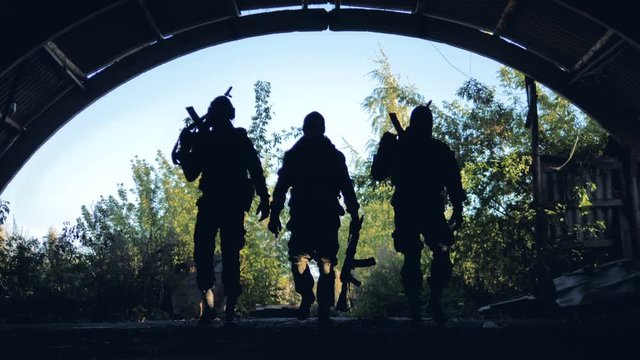Three silhouettes of armed soldiers moving to the camera.
