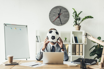 businessman covering face with soccer ball