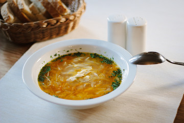 Soup at white ceramic plate at the table.