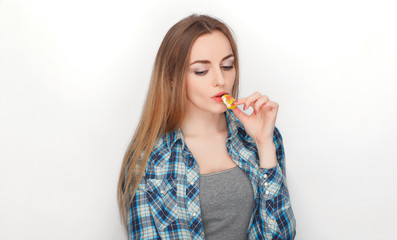 Beauty portrait of young adorable fresh looking blonde woman in blue plaid shirt posing with candy lollipop. Emotion and facial expression concept.