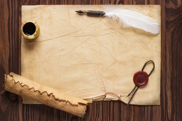 Closeup of scroll and quill near ink-pot on wooden table