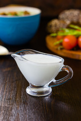Natural cream dip in a glass bowl on dark wooden board.