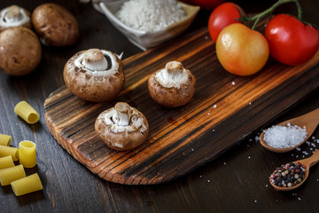 Mushrooms on board with fresh vegetables on background.