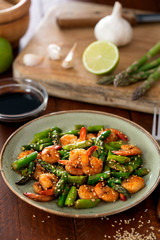 Salad with asparagus and shrimps in plate. Ingredients on the table