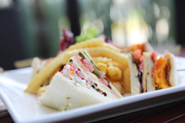 Club sandwich with chicken breast , bacon , tomato , cucumber and fried potatoes