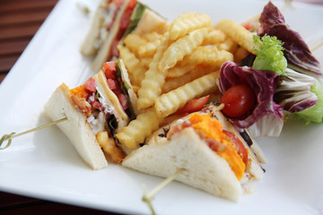 Club sandwich with chicken breast , bacon , tomato , cucumber and fried potatoes