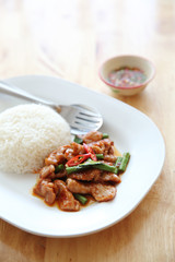 fried pork with thai curry and rice on wood background , Thai food