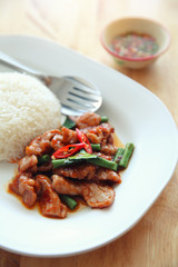 fried pork with thai curry and rice on wood background , Thai food