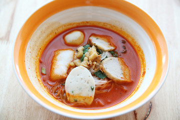 Fish and fishball Tom yum noodle on wood background , Thai food