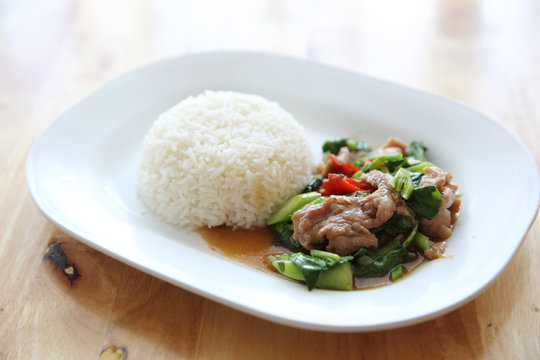 fried pork with Chinese Kale and rice on wood background , Thai food