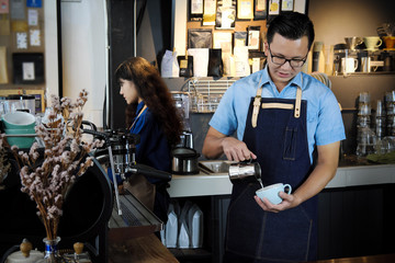 Portrait of barista making latte or cappucino coffee in coffee shop. Cafe restaurant service, food and drink industry concept.