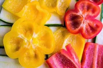 View from above on fresh red and yellow cut sliced peppers and zucchinis