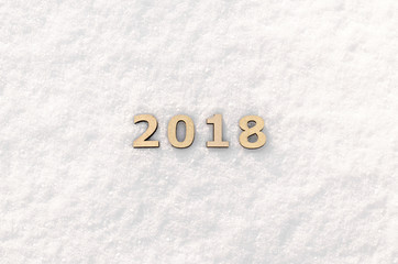 Wooden numbers forming the number 2018 on white snow sparkling in the sun backgraund texture