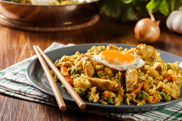 Fried rice nasi goreng with chicken egg and vegetables on a plate.
