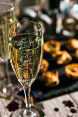 New Year: Glass Of Champagne With Party Food Behind