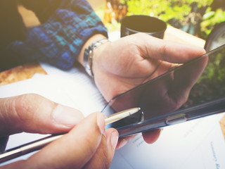 Close up hand of businessman holding tablet on wooden table.