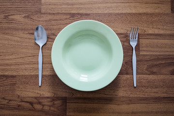 Empty Green Dish with Stainless Forks and Spoon, on Wood Texture Background