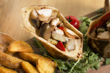 Burrito with grilled chicken and vegetables. Shawarma from juicy beef, lettuce, tomatoes, cucumbers, paprika and onion in pita bread.
