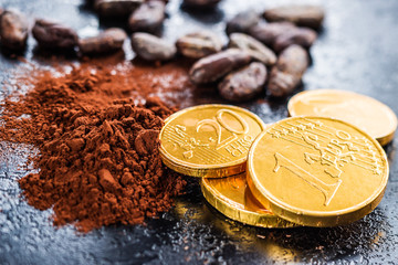 Dark cocoa powder, cocoa beans and chocolate coins.