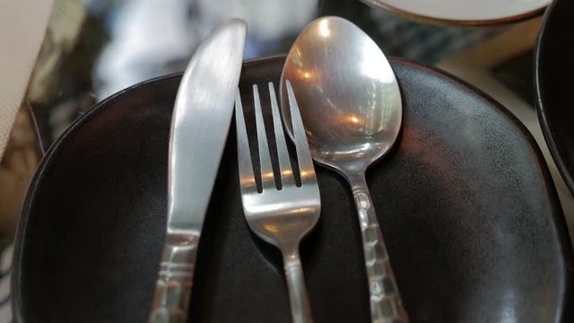 cutlery set of spoon and fork and knife on black plate in restaurant