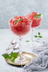 Watermelon granite with mint, summer refreshing drink in glass on a gray concrete background. Selective focus.