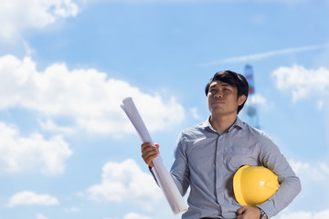 The engineers holding the blue print stand at the job site.