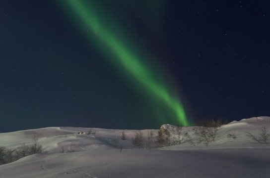 Northern lights in winter over snowy hills.
