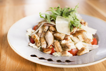 Salad with chicken, mozzarella and cherry tomatoes. Caesar salad served at a restaurant.