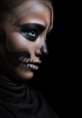 Closeup profile of a girl with make-up skeleton. Halloween portrait. Isolation on a black background